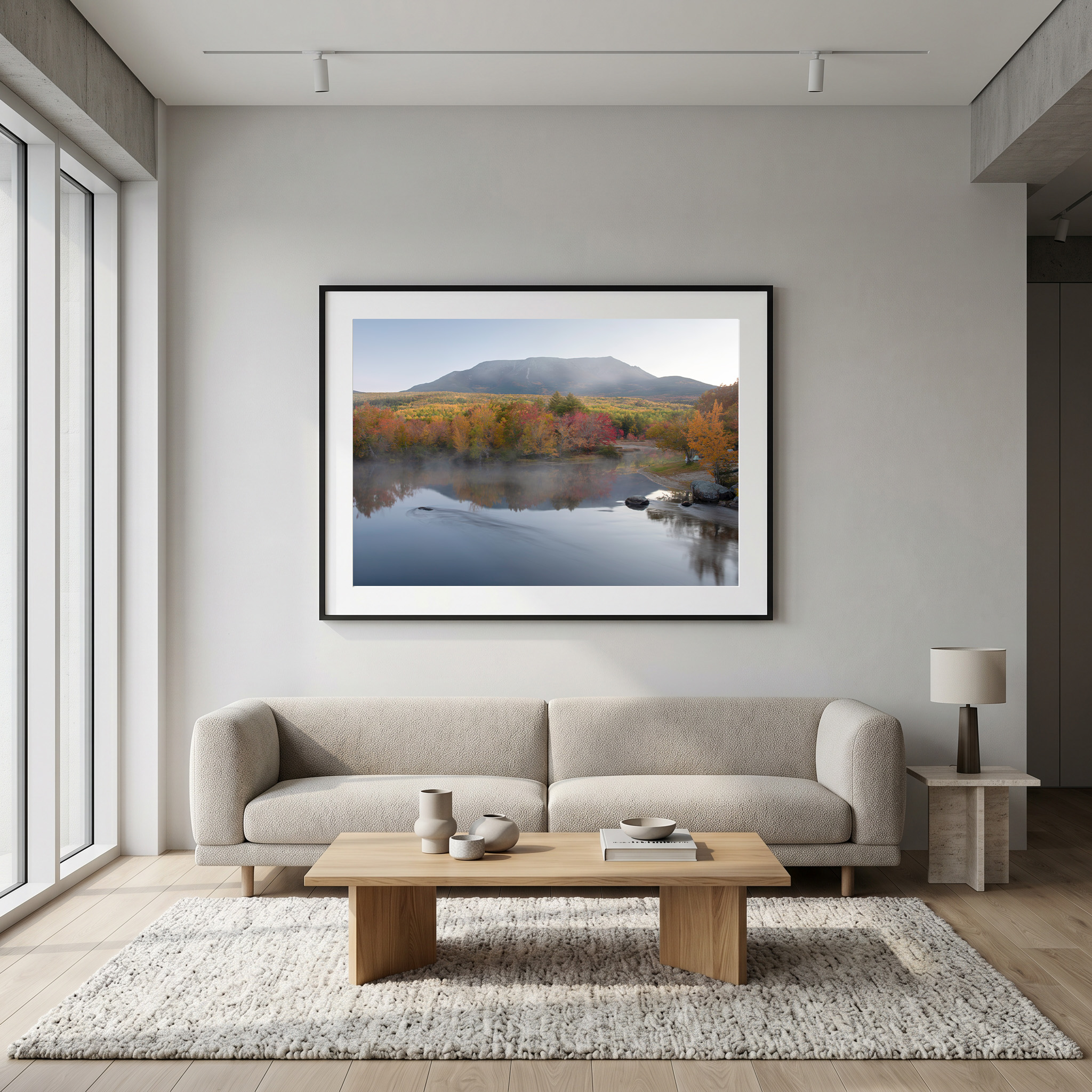 Modern neutral living room with framed Maine lake autumn landscape by Dan Sproul — black frame above sofa